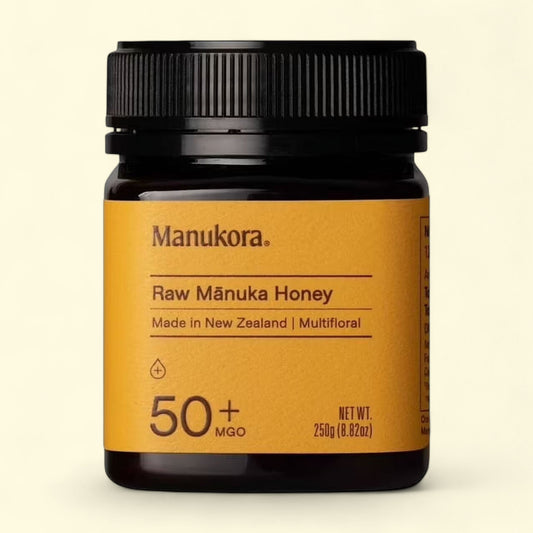 Manukora Raw Manuka Honey jar with a black lid on a beige background