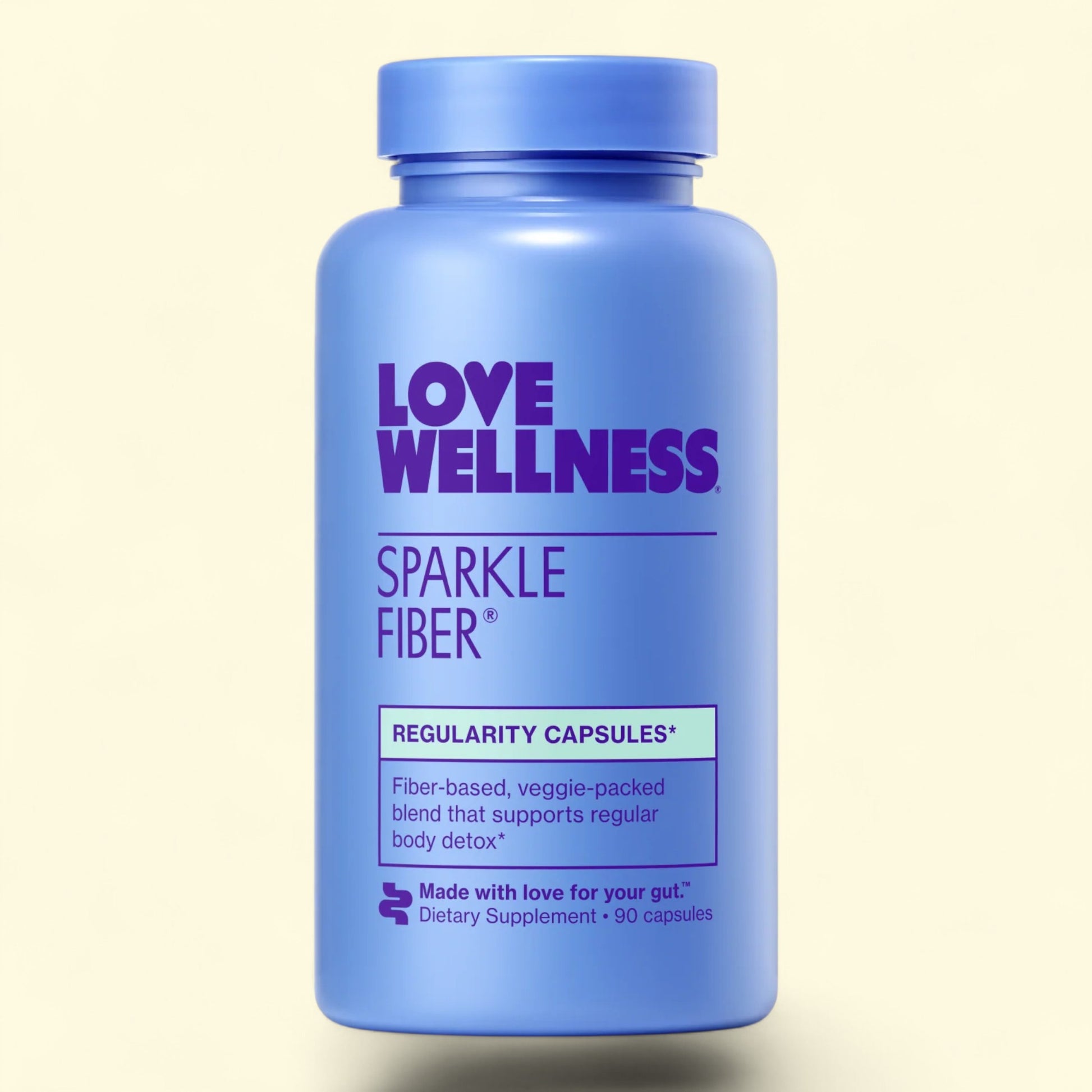 Blue supplement bottle labeled 'Love Wellness Sparkle Fiber' on a beige background