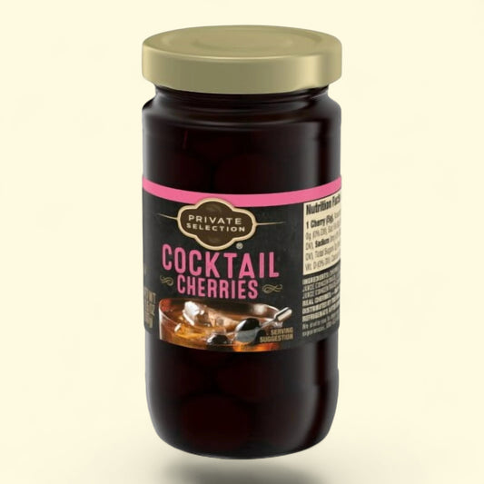 Jar of cocktail cherries with a gold lid on a beige background